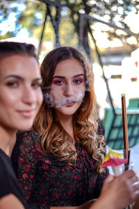 Portrait of woman exhaling smoke with friend in restaurant
