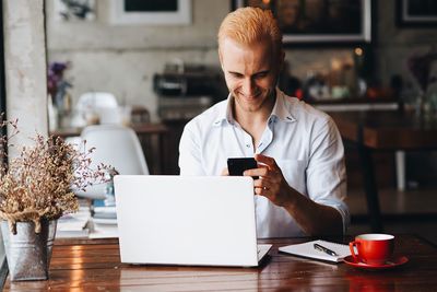 Man holding coffee while sitting on table at cafe