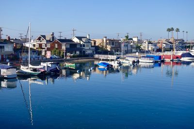 Boats moored in water against clear blue sky