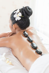 Rear view of woman with stones on back lying at health spa