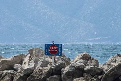 Information sign on rock by sea against sky