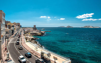 High angle view of road by sea against blue sky