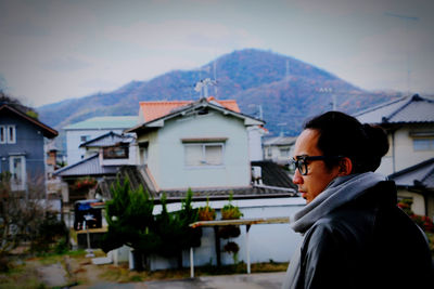 Side view of a young woman against buildings