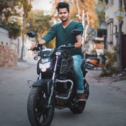 Portrait of young man riding motorcycle on road