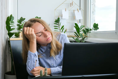 Young woman using phone while sitting on table