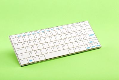 High angle view of computer keyboard on green background