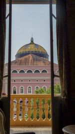 View of historic building against sky seen through window