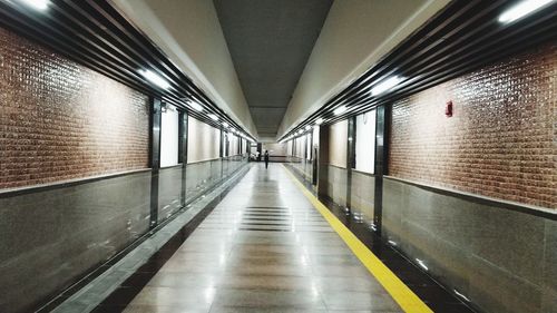 Rear view of woman walking in illuminated tunnel