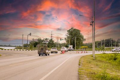 Cars on road against sky during sunset