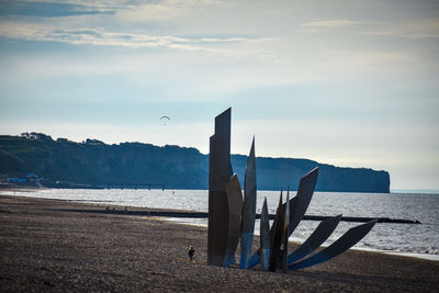 Deck chairs on beach against sky