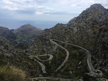 Scenic view of country road by mountains against sky