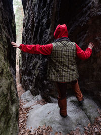 Woman with red hood walk between rocks. rocky formation of big sandstone massif.