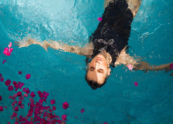 High angle view of woman swimming in pool full of flowers 