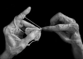 Close-up of man holding hands against black background