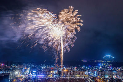 Firework display in city against sky at night
