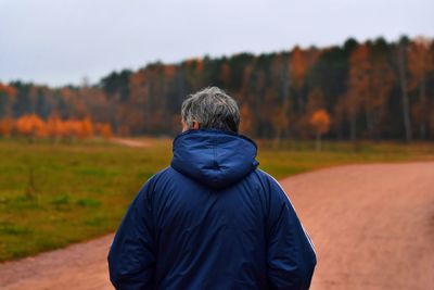 Rear view of man standing on field against sky