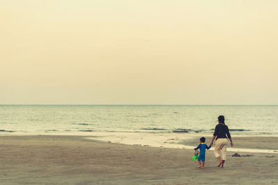 Rear view of people at beach against sky