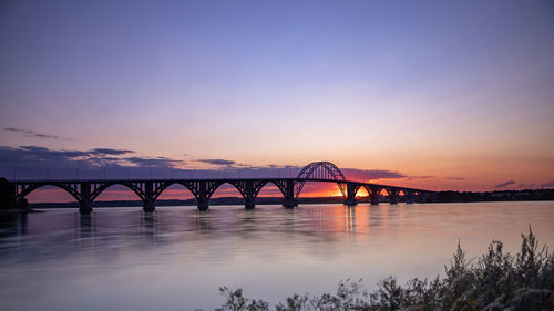 Bridge over river against romantic sky at sunset