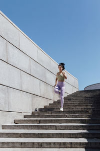 Female athlete running on steps during sunny day