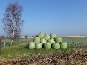 Stack of hay on field against clear sky