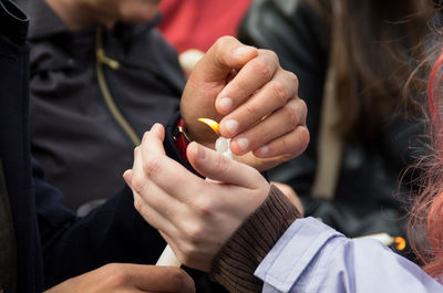 Cropped hands of man and woman covering lit candle