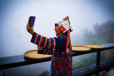 Side view of mature woman wearing traditional clothing while taking selfie with mobile phone