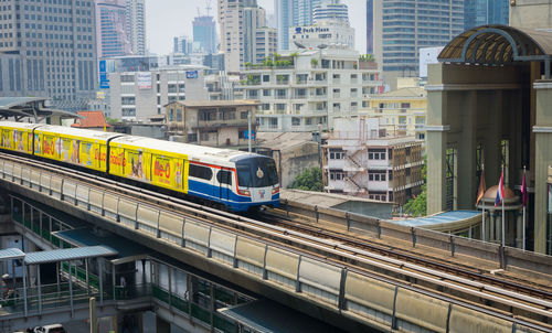 Train on railroad tracks by buildings in city