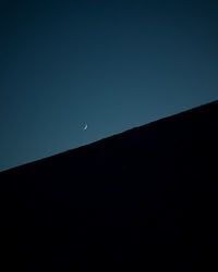 Low angle view of silhouette moon against clear blue sky