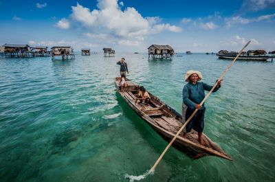 Men in boat on sea against sky