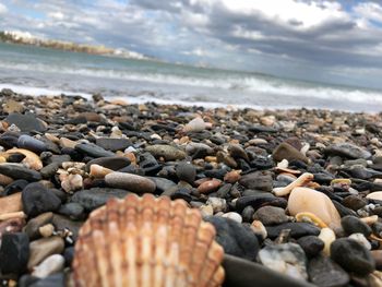 Close-up of pebbles on beach against cloudy sky