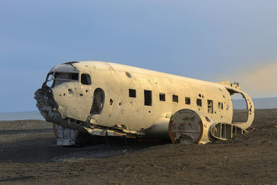 Abandoned airplane on sand against sky