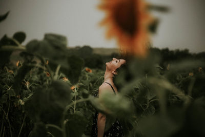 Young woman standing amidst sunflowers on field