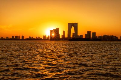 Modern cityscape against sky during sunset