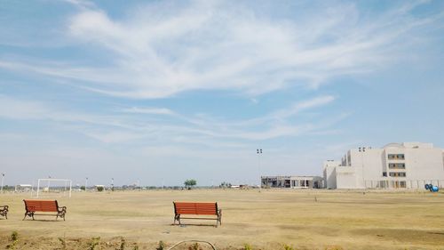 Benches on field against sky