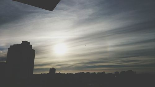 Silhouette buildings against sky at sunset