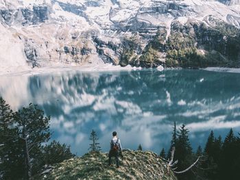 High angle view of man standing on rock by lake against mountain