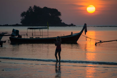 Silhouette man in sea against sky during sunset