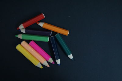 Close-up of multi colored pencils on table against black background