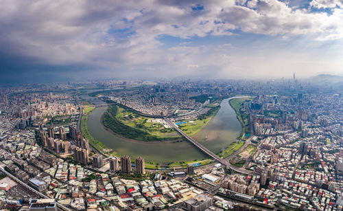 High angle view of city buildings against cloudy sky