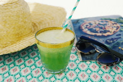 Close-up of drink with hat and sunglasses on table