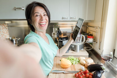 Portrait of smiling woman holding food at home