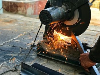 Cropped hand of man cutting metal with electric saw