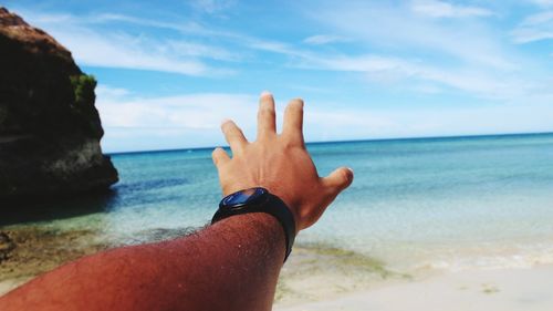 Midsection of person on beach against sky