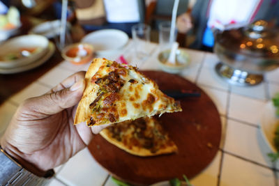 Close-up of hand holding pizza