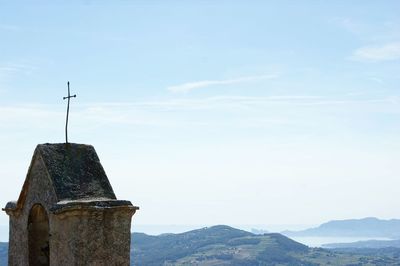 Low angle view of cross on mountain against sky