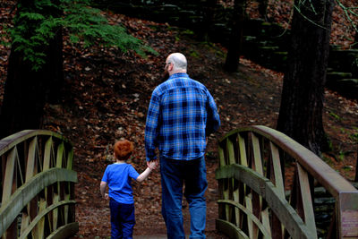 Rear view of father and son walking on footbridge