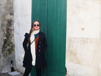 Portrait of smiling young woman standing against wall