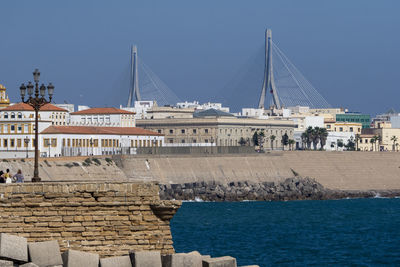 Sailboats in sea against buildings in city