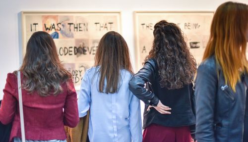 Rear view of women standing in front of text on wall