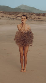 Rear view of woman standing on sand at desert